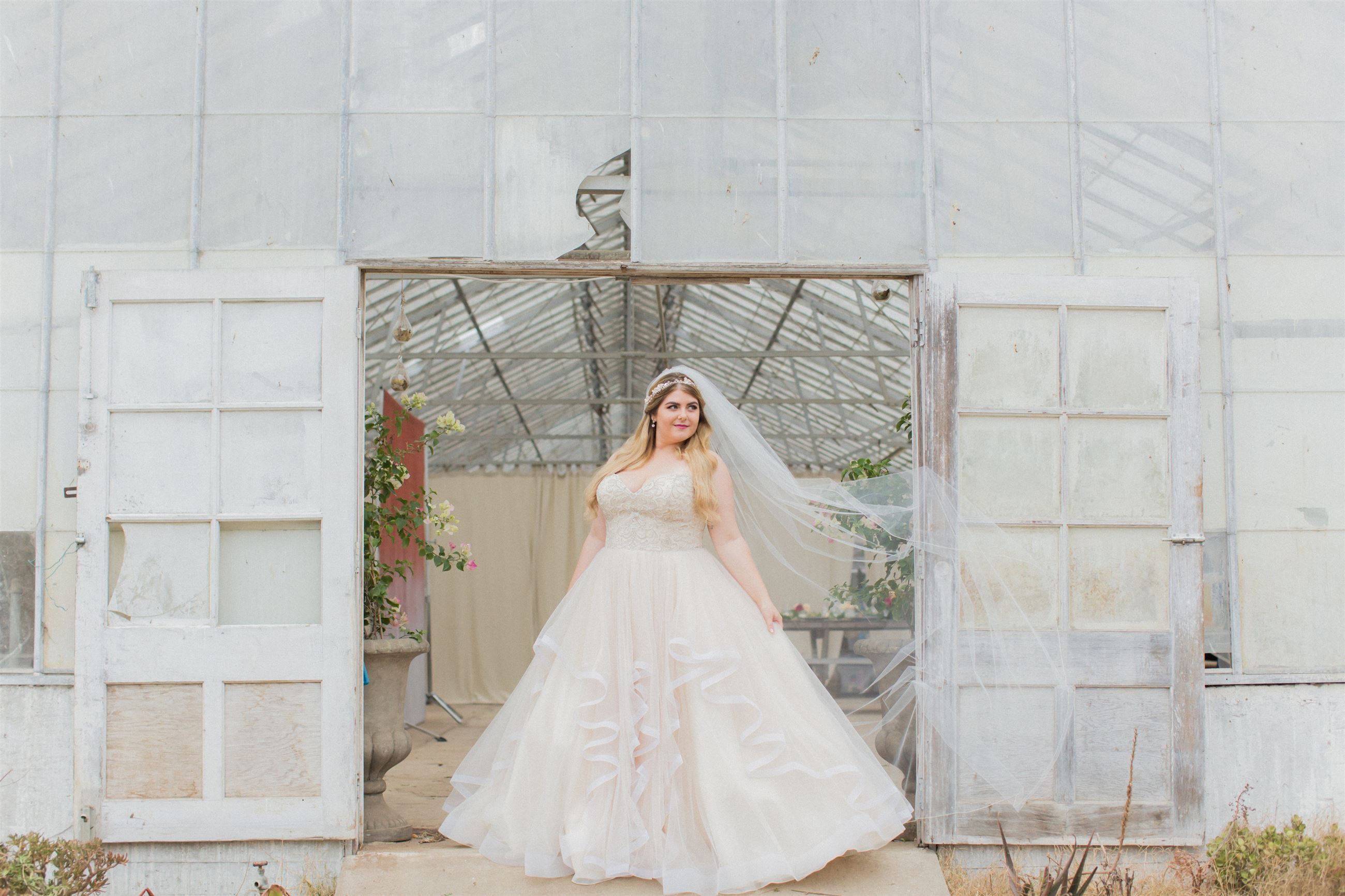 Blonde bride with veil in white dress near hangar