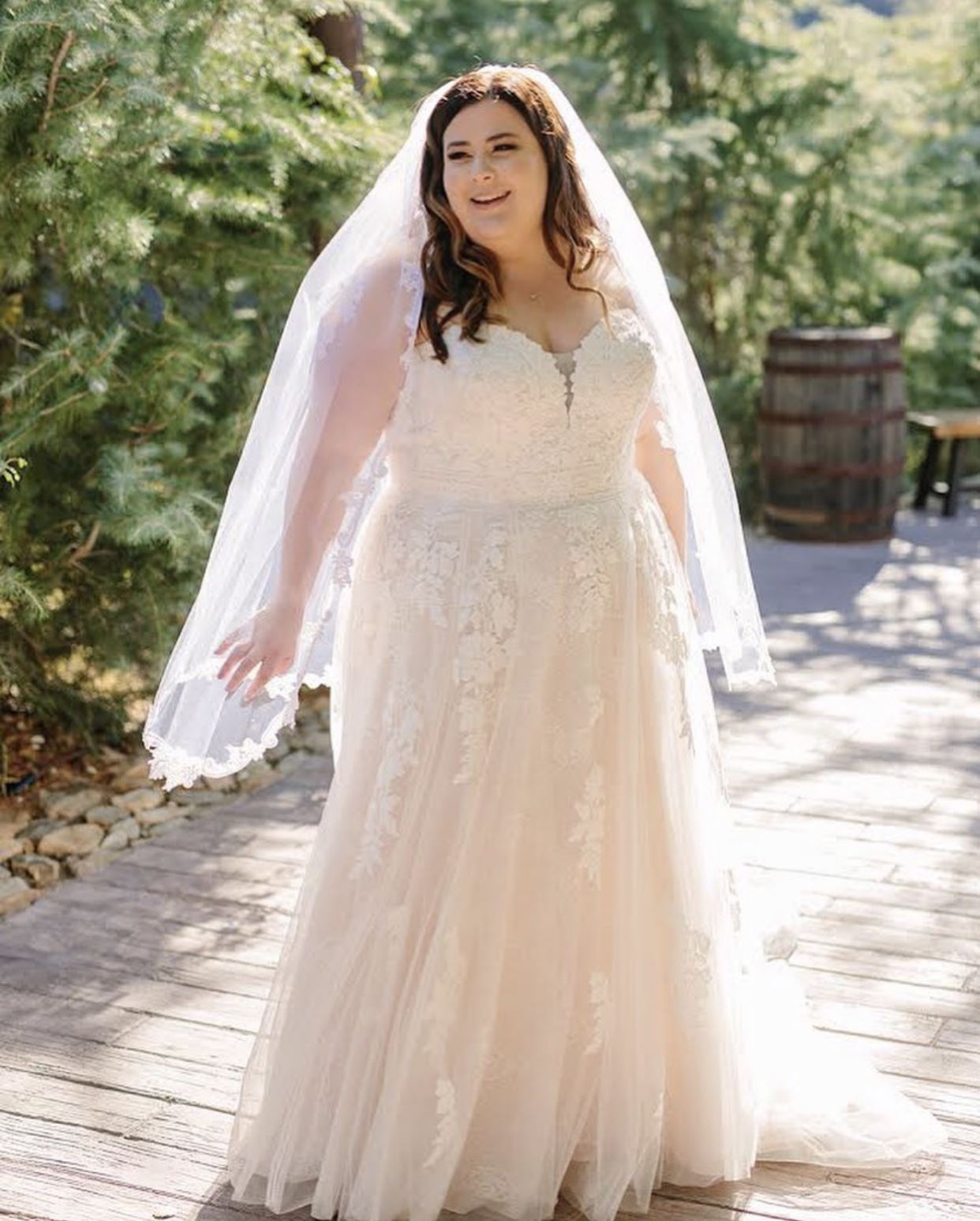 Brunette bride in white wedding dress with veil at countryside