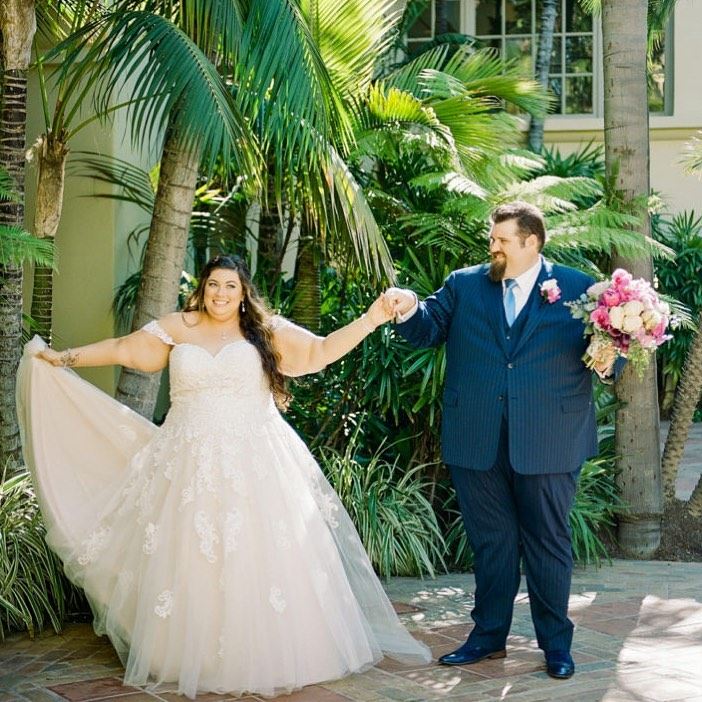 Bride in white wedding dress near tropic trees together with groom