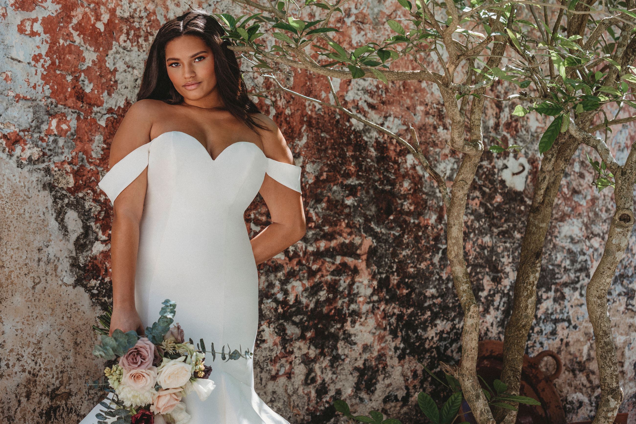 Bride in white wedding dress near the wall