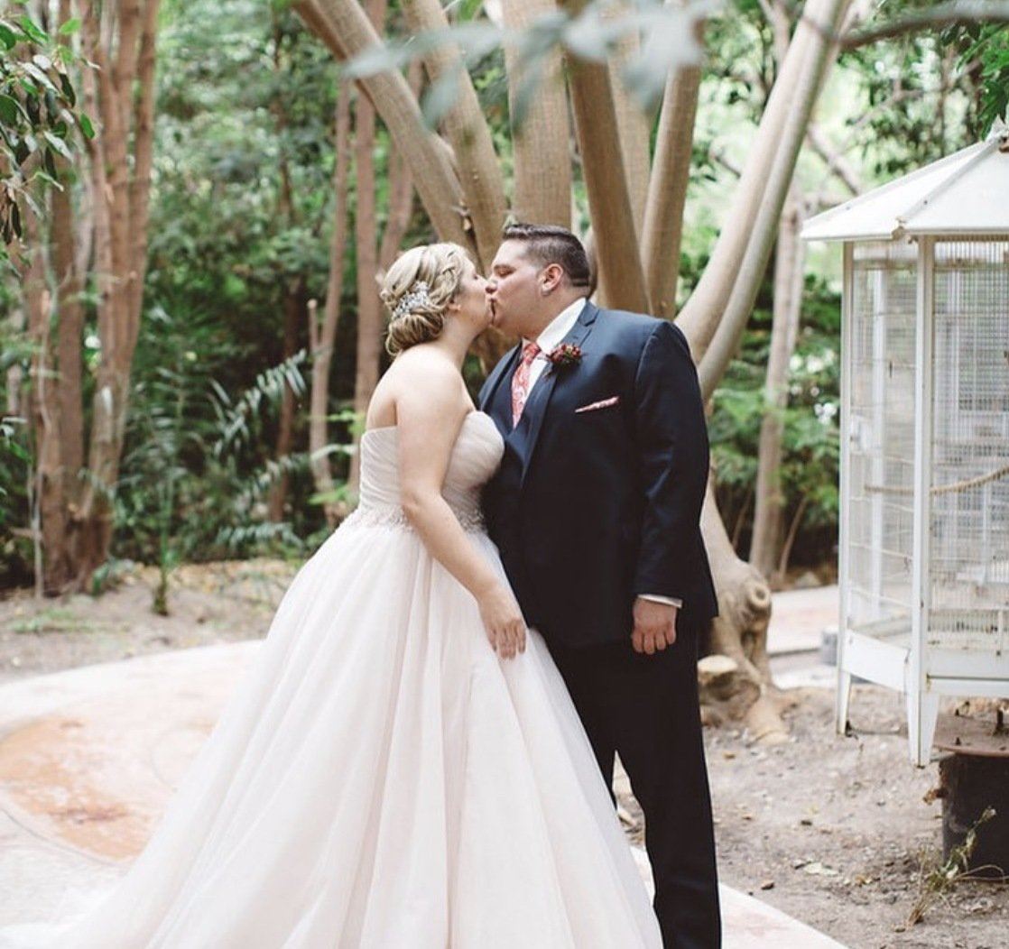 Blonde bride in beige wedding dress is kissing groom