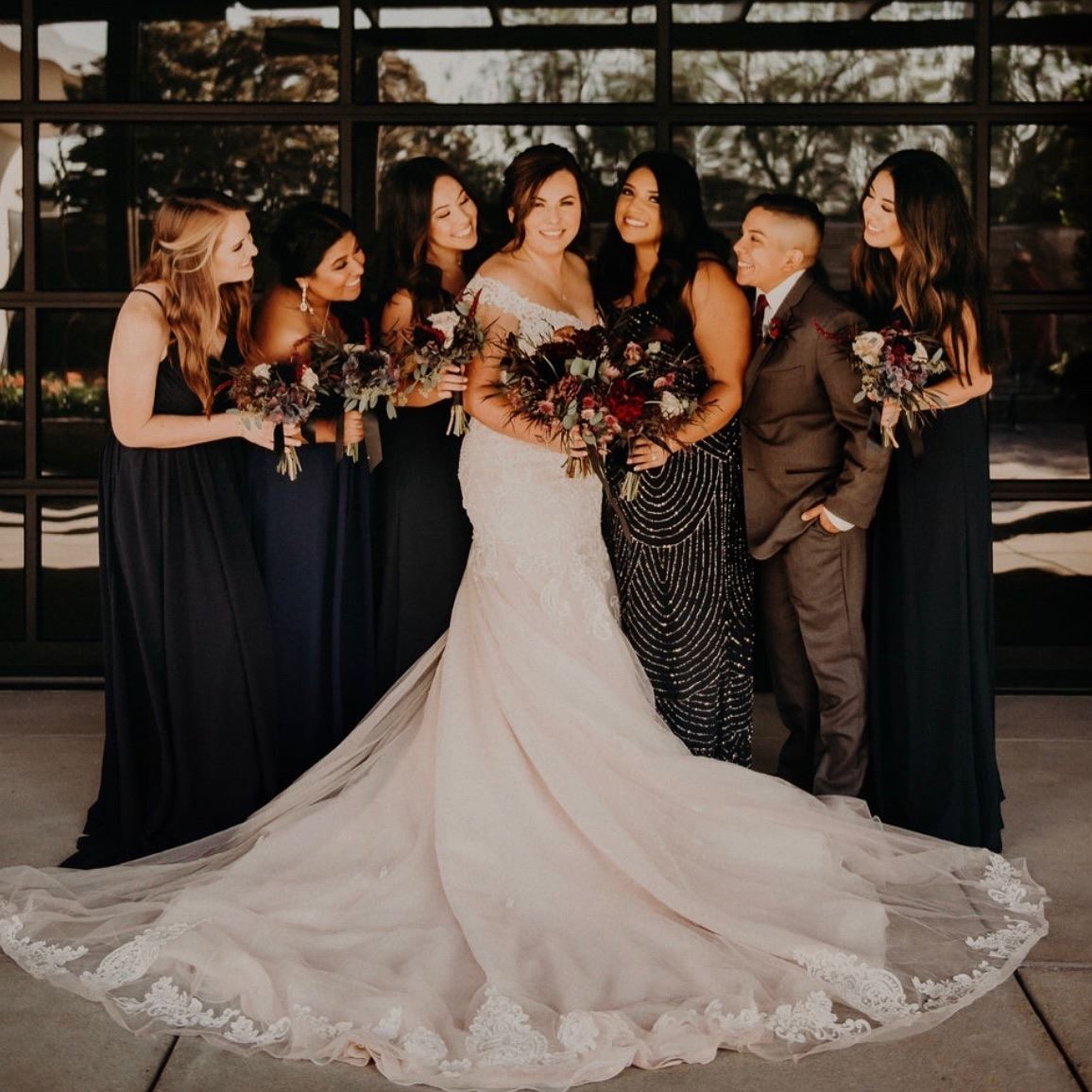 Bride in white wedding dress with flowers surrounded bridesmaids